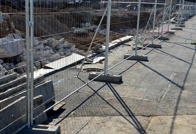 metal temporary fence panels surrounding a public property to deter vandalism